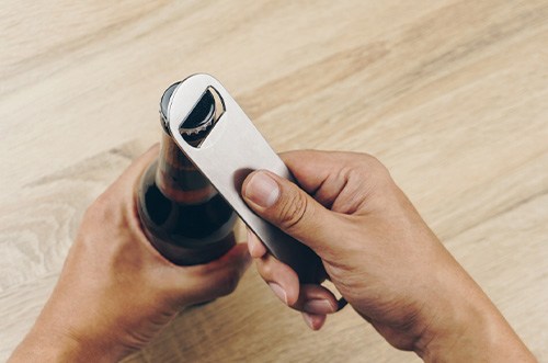Hands using bottle opener on bottlecap