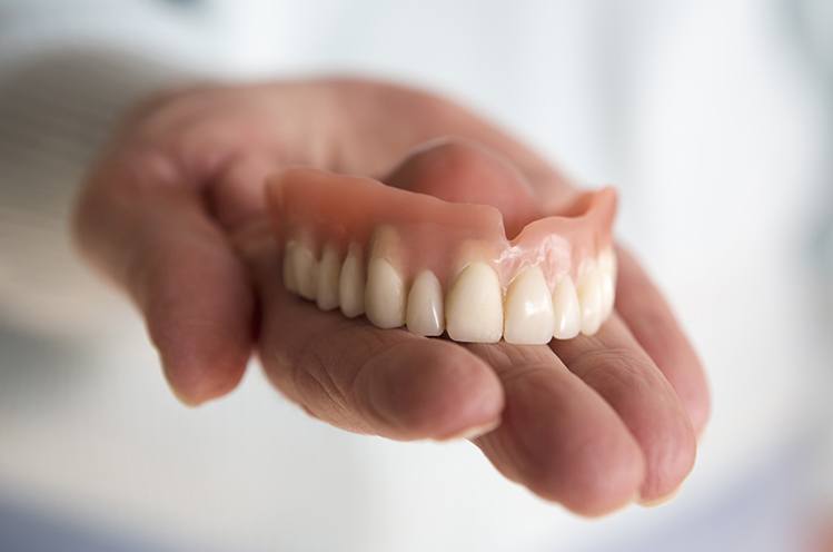 Hand holding an upper denture
