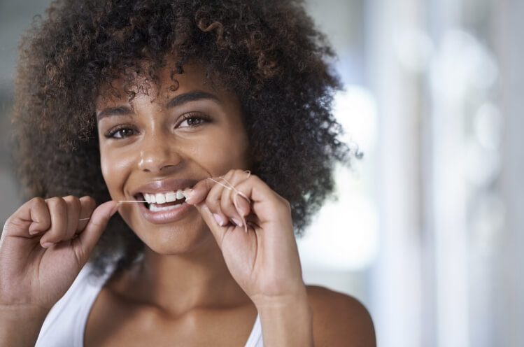 Woman flossing teeth to prevent dental emergencies