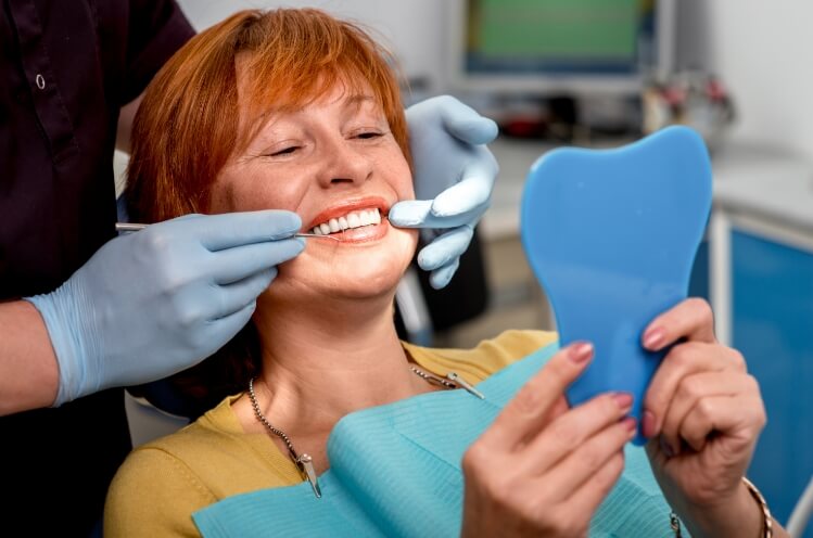 Woman looking at smile after tooth replacement with dental implants
