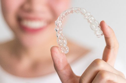 Closeup of patient holding Invisalign aligner