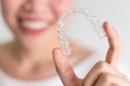 Closeup of patient holding Invisalign aligner 