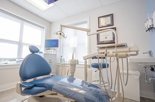 Dentist smiling at patient while holding Invisalign aligner 