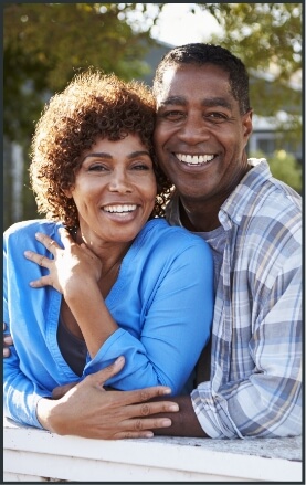 Man and woman with full smiles thanks to tooth replacement with dental implants