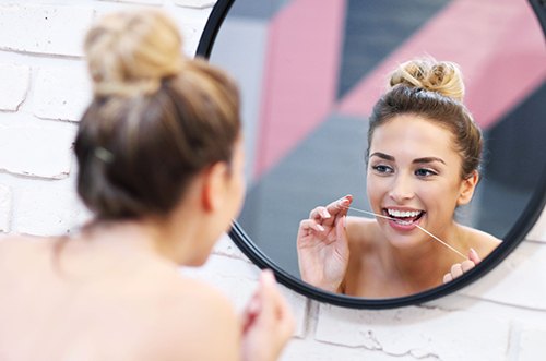 woman flossing for teeth whitening in East Gwillimbury