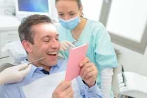 Man smiling and looking into mirror after cosmetic dental treatment